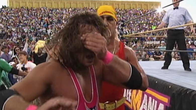 Hulk Hogan standing behind a blinded Bret Hart