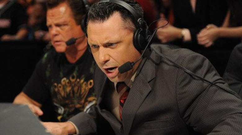 Michael Cole sits beside Jerry Lawler on the commentary desk during an episode of WWE TV.