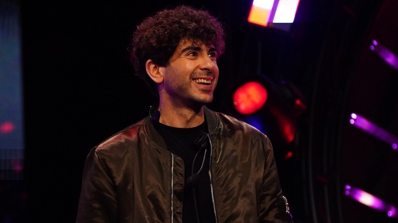 AEW President Tony Khan smiles at the crowd from the top of an AEW entrance ramp