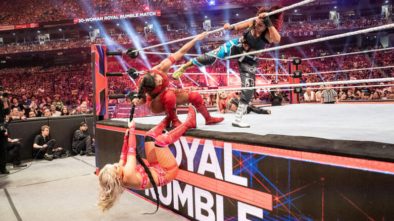 Tiffany Stratton hangs on Bianca Belair's braid as Bayley attempts to kick Belair for a Royal Rumble elimination.