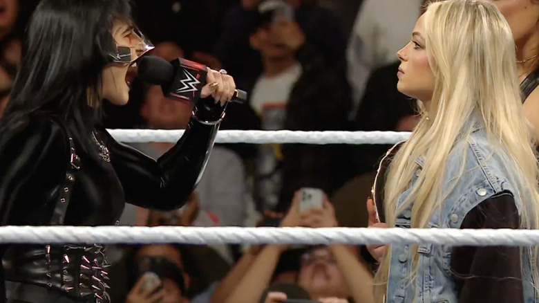 Rhea Ripley wearing face mask shouts at Liv Morgan through a microphone on "WWE Raw."