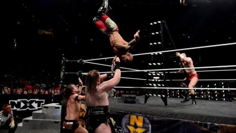 Ricochet dives out of the ring onto Adam Cole, Killian Dain, and Lars Sullivan