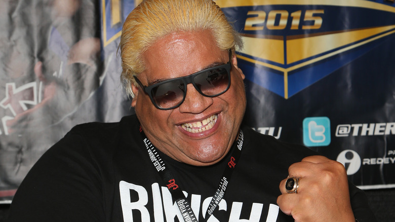 WWE Hall of Famer Rikishi is wearing sunglasses and smiling