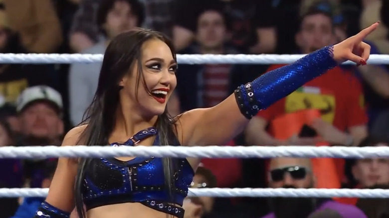 Roxanne Perez grins as she points to an off-screen WrestleMania sign.