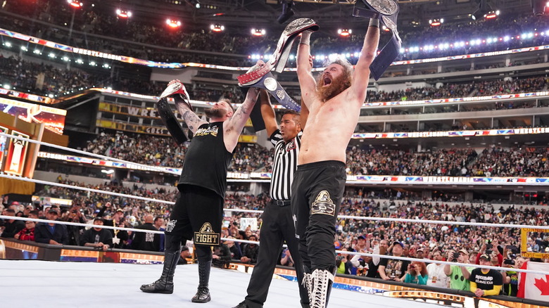 Sami Zayn and Kevin Owens raise their titles