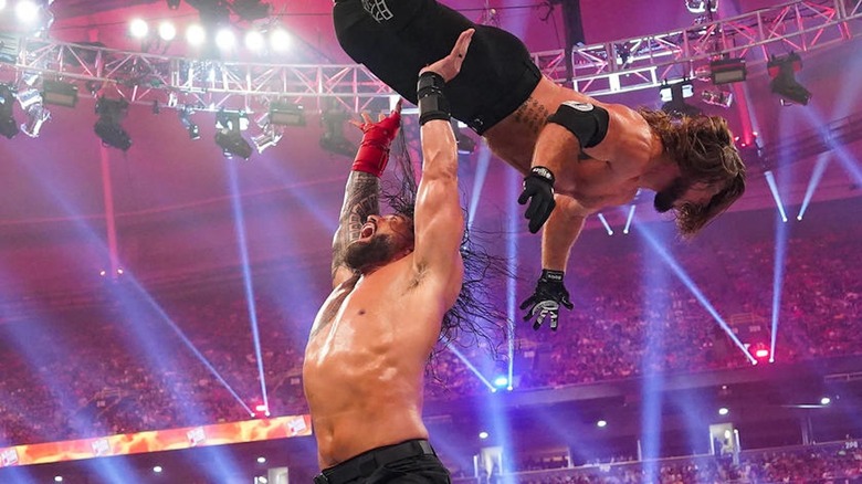 Roman Reigns launches AJ Styles high over his head.