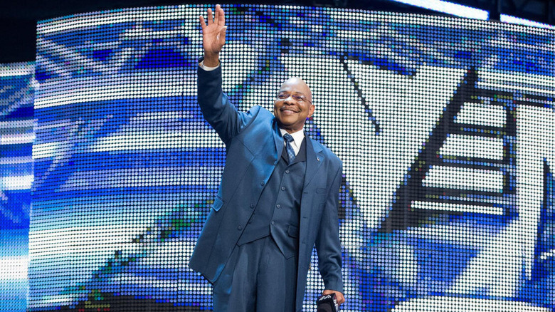 Teddy Long waves to the crowd with a wide smile on his face