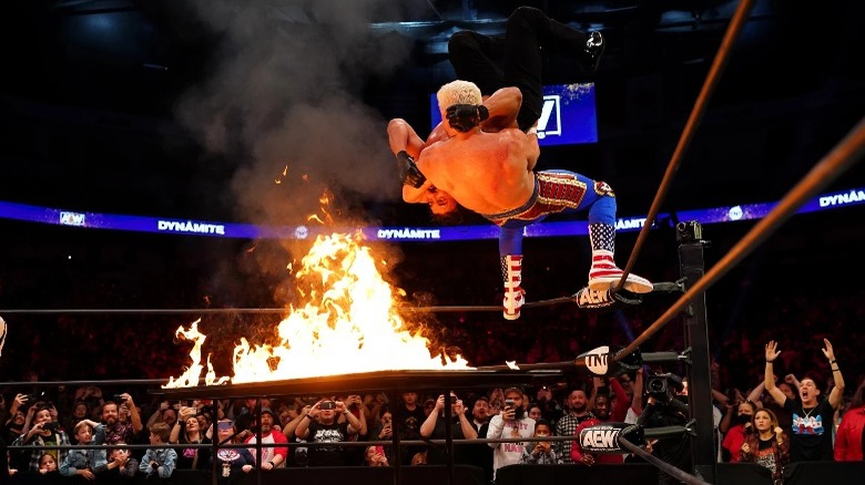Cody Rhodes suplexing Andrade through flaming table