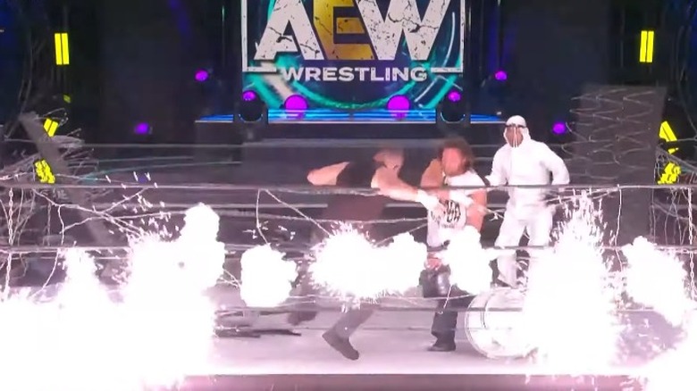 Kenny Omega throwing Jon Moxley into exploding barbed wire