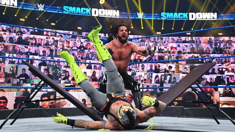 Seth Rollins powerbombs Rey Mysterio through a table
