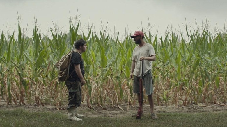 Two men stand in field