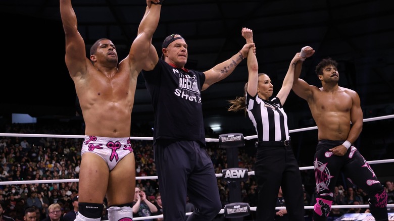 The Acclaimed, composed of Anthony Bowens, Billy Gunn, and Max Caster, all raise their hands alongside referee Aubrey Edwards.