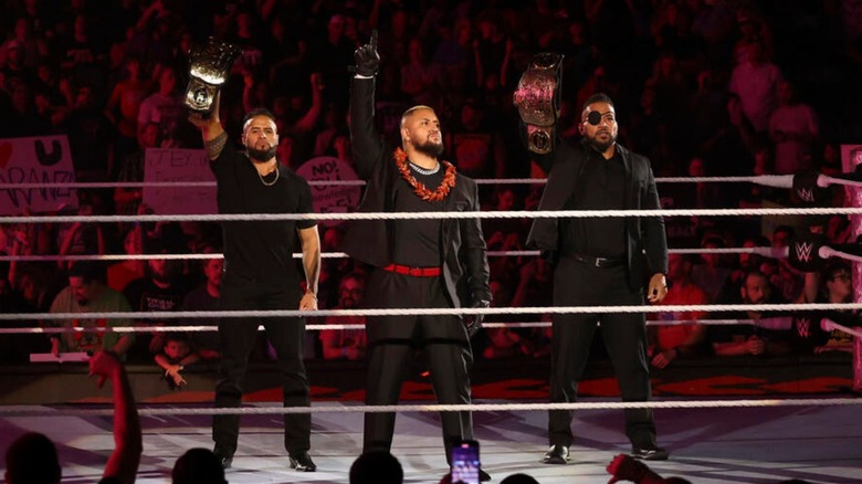 Tama Tonga, Solo Sikoa, and Tanga Loa stand in the ring, with the WWE Tag Team Championships 