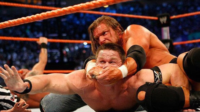 Triple H puts John Cena in a cross face maneuver in the middle of the ring during a triple threat match at WrestleMania 24.