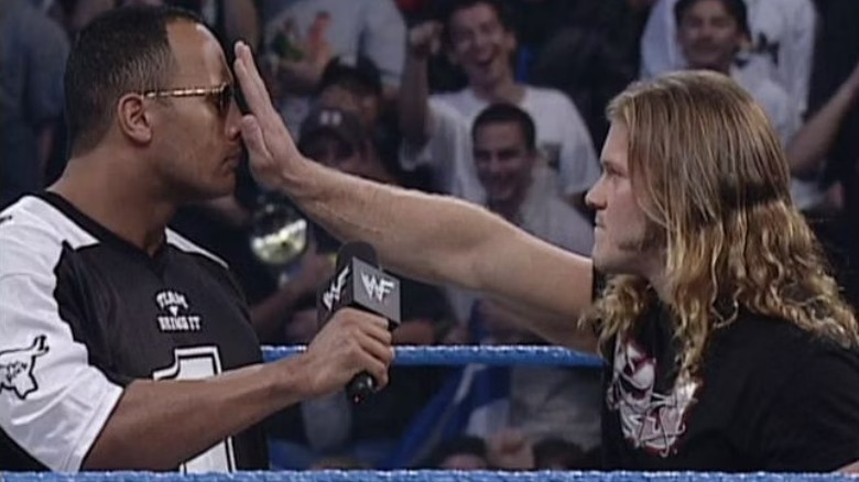 Chris Jericho with his hand in the Rock's face