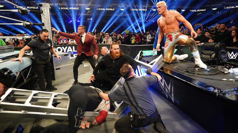 Sami Zayn checks on Kevin Owens while Cody Rhodes looks on after putting Owens through a ladder at WWE Royal Rumble