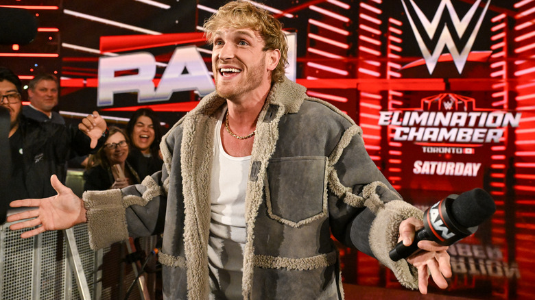 Logan Paul spreads his hands and smiles while holding a microphone on "WWE Raw"