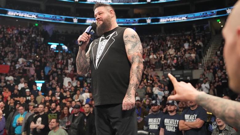 Kevin Owens stands on table with microphone on "WWE SmackDown."