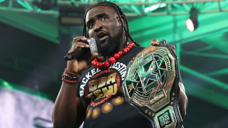 NXT Champion Oba Femi holds up the title while cutting a promo in the ring during 