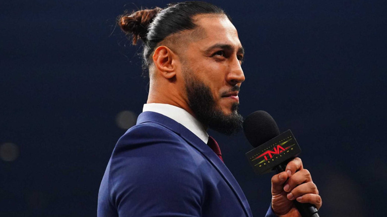 Mustafa Ali holding a microphone