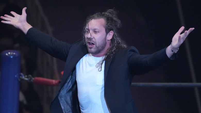 Kenny Omega with arms wide open, under the sunlight