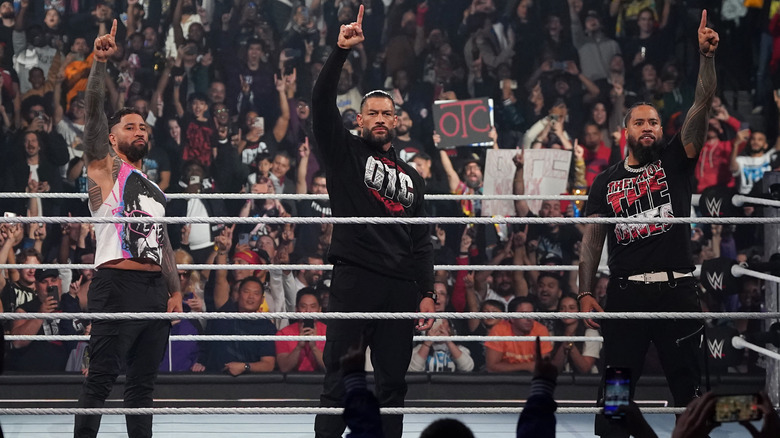 Jey Uso, Roman Reigns, and Jimmy Uso each holding up a finger