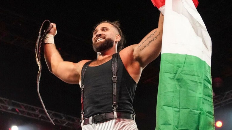 Tony D'Angelo holds up the NXT North American Championship in one hand, the Italian flag in the other, while standing on the turnbuckle during an episode of 