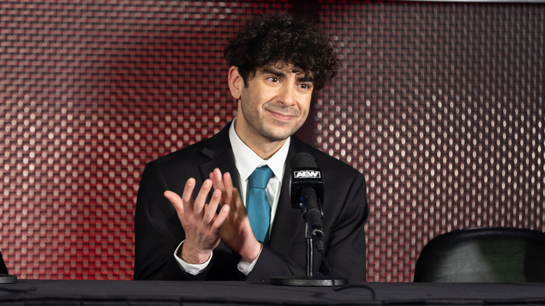 Tony Khan applauding at a media scrum