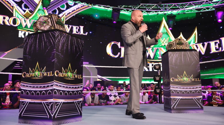 WWE CCO Paul "Triple H" Levesque standing between the two Crown Jewel Championship belts.