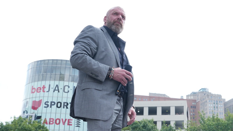 Paul Levesque looking off into the distance, holding microphone