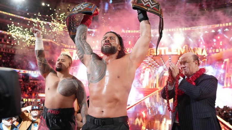 Roman Reigns holds up his titled with Solo Sikoa and Paul Heyman