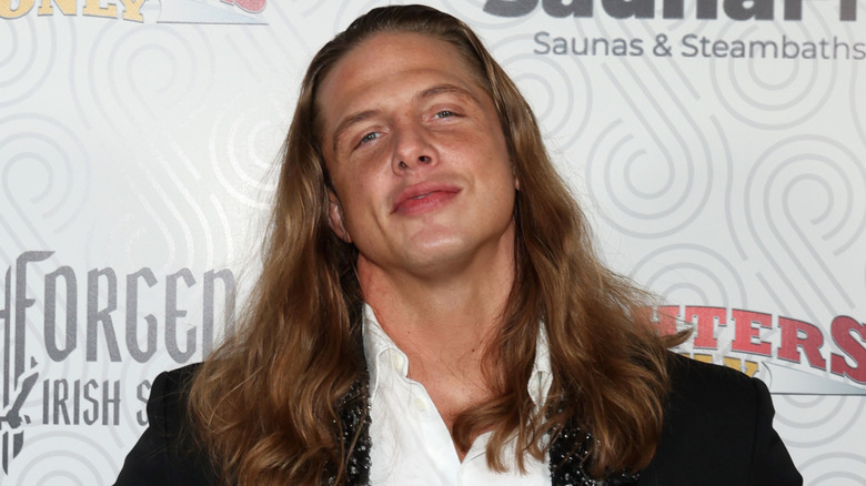 Matt Riddle smiles towards the camera at a red carpet event