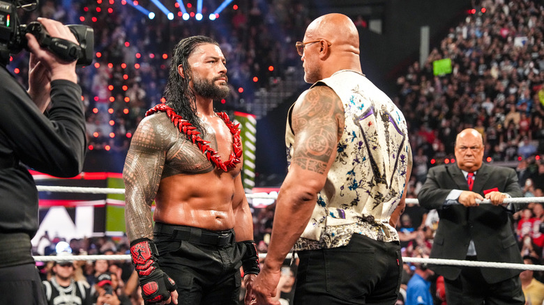 The Rock presents Roman Reigns with the ula fala