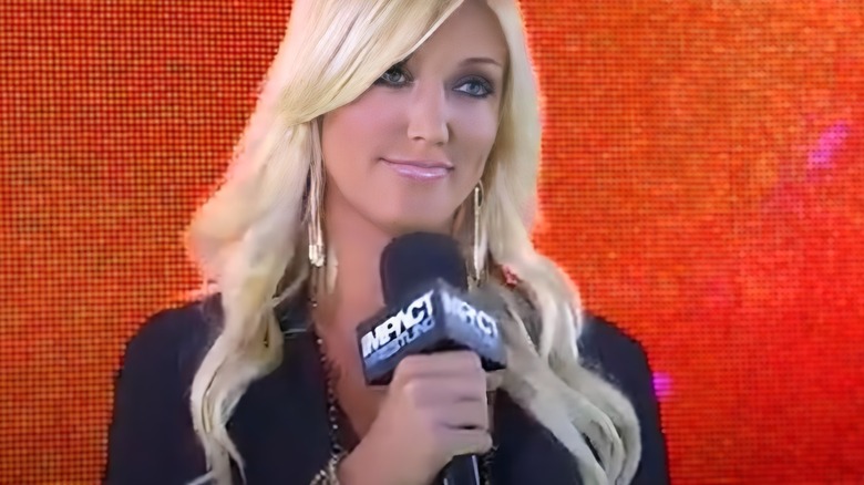 Brooke Hogan appears on stage at a TNA Wrestling show, microphone in hand.