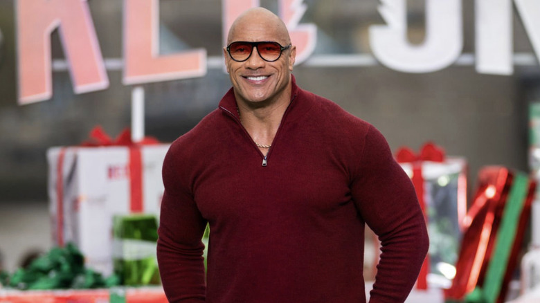 Johnson appears in a red quarter-zip and red-tinted shades at a Christmas-themed "Red One" promotional event.