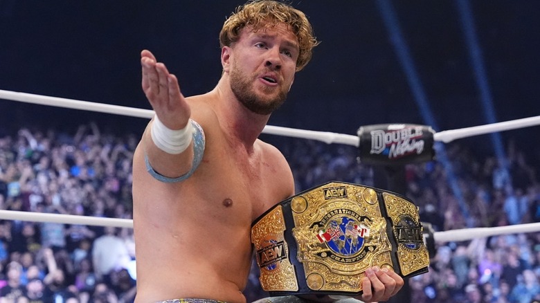 Will Ospreay gesturing while holding AEW title belt in wrestling ring