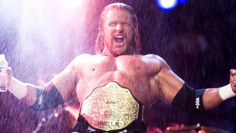 Triple H poses, wearing his World Heavyweight Championship, after spitting water in the air on the apron of the ring before a match.