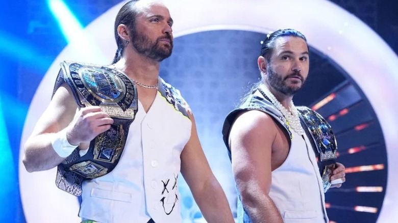 Matthew and Nicholas Jackson, the Young Bucks, walk to the ring holding their AEW Tag Team Championships on an episode of AEW programming.