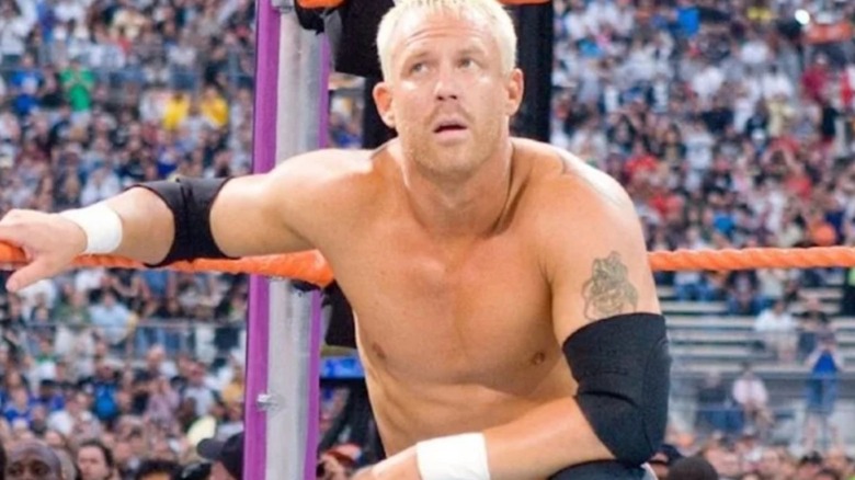 Mr. Kennedy crouches in the corner, a wary look on his face, during a match in WWE.