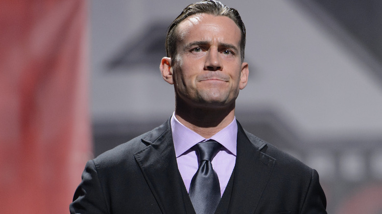 CM Punk wearing suit, pursing lips