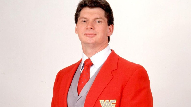 Vince McMahon stands smirking in his WWF commentator's jacket for a photo.