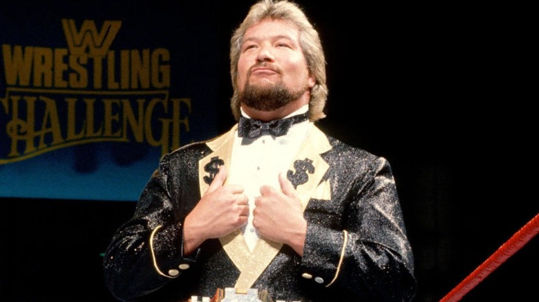 Ted DiBiase stands in the middle of the ring, posing for the camera.