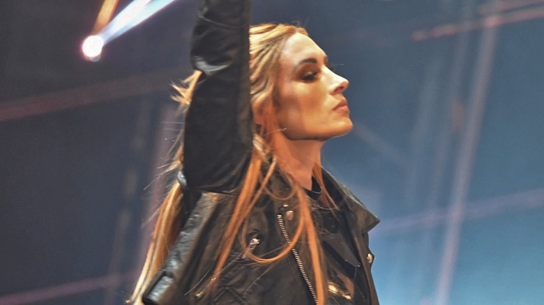 Becky Lynch wearing black leather jacket, raising right arm