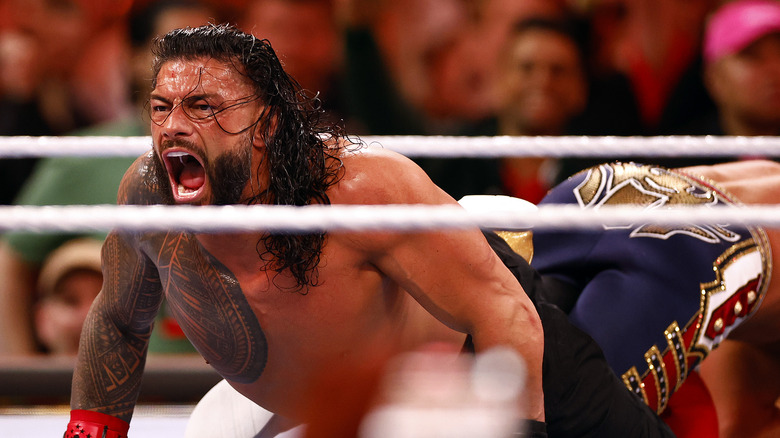 Roman Reigns in the ring, screaming in pain from submission hold