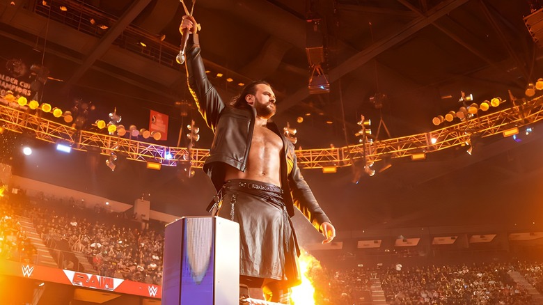 Drew McIntyre raising sword amidst fire