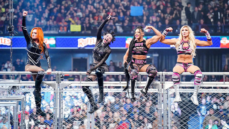 Becky Lynch, Shotzi, Bianca Belair and Charlotte Flair sitting on top of a cage