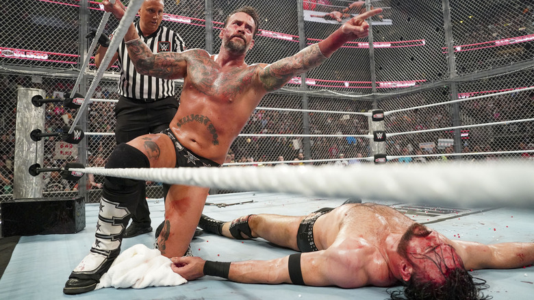 CM Punk points while Drew McIntyre lies motionless