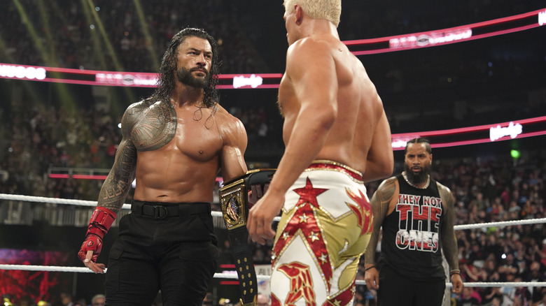 Roman Reigns handing Cody Rhodes his title belt