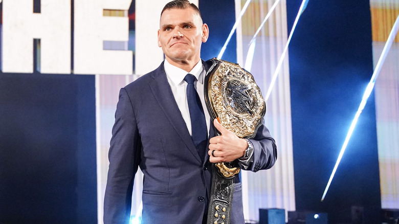 GUNTHER in suit with title belt on his shoulder