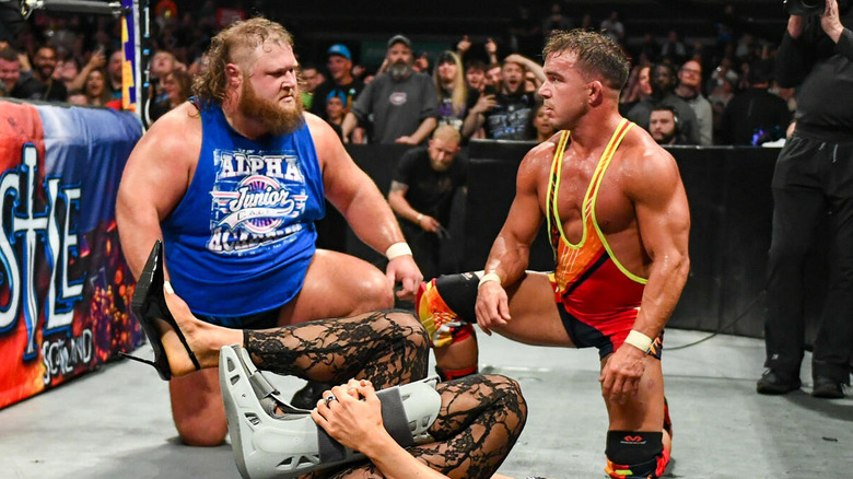 Otis and Chad Gable stare each other down in front of a fallen Maxxine Dupri